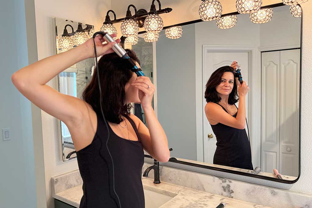 Woman with thick, mid-length hair wrapping sections around the BaBylissPRO Nano Titanium Compact Curling Wand.