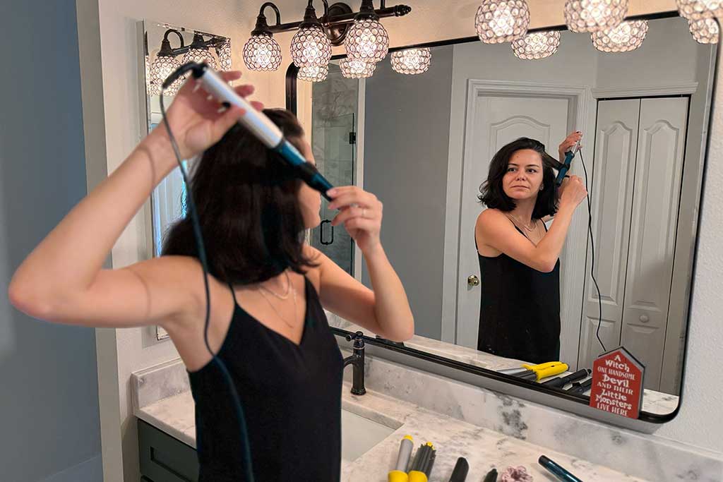 Woman with mid-length hair styling with the BaBylissPRO Nano Titanium Curling Wand.
