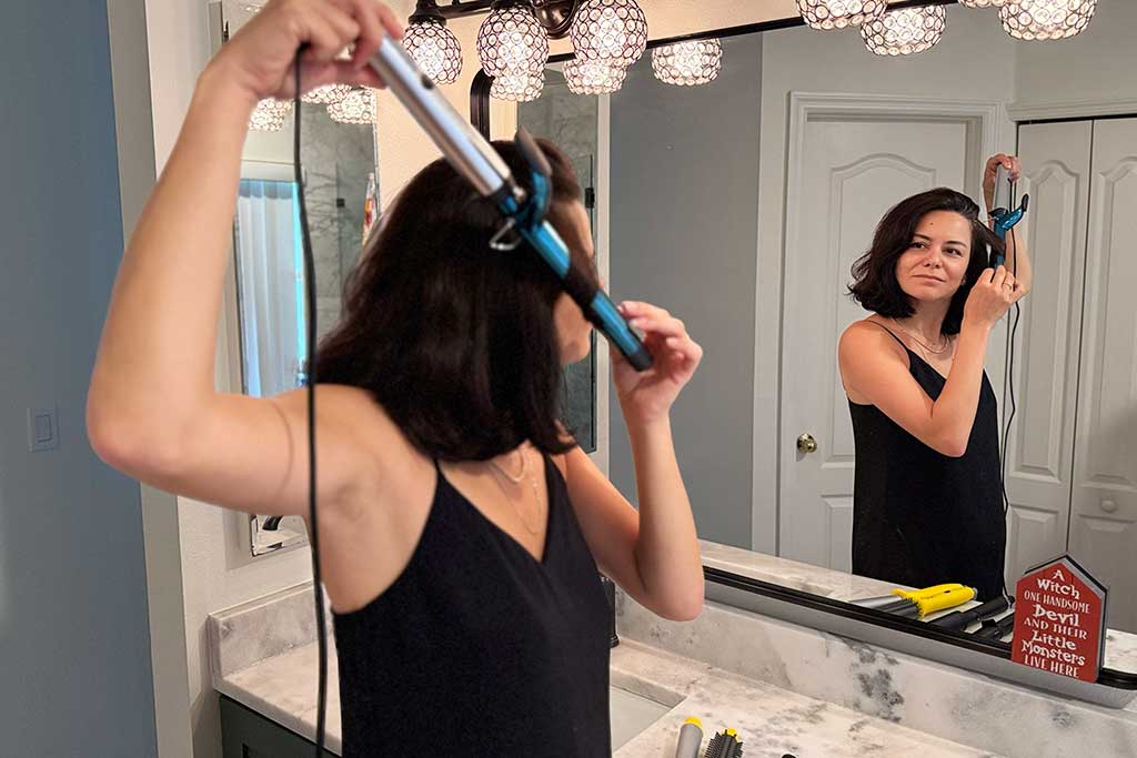 Woman with mid-length hair using the BaBylissPRO Extended Barrel Curling Iron to style large sections.