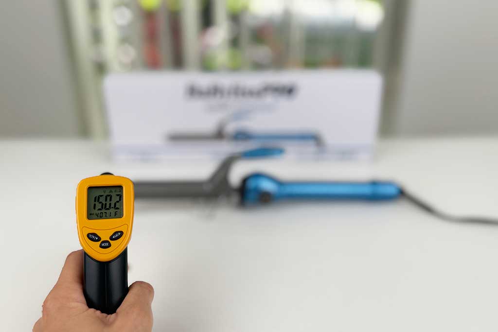 Thermometer pointed at the BaBylissPRO Nano Titanium Spring Curling Iron’s cool tip reading 150°F.