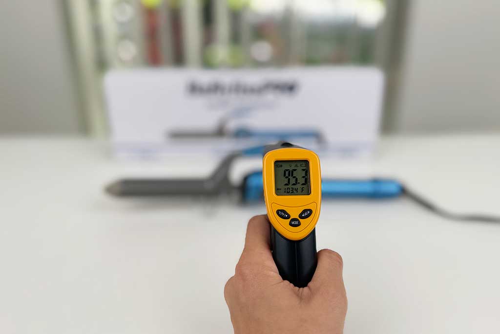 Infrared thermometer reading 95°F on the finger grip area of the BaBylissPRO Nano Titanium Spring Curling Iron.