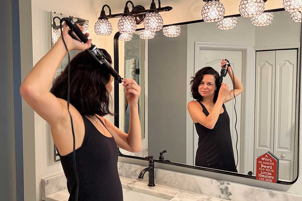 Woman styling mid-length hair with the BaBylissPRO Porcelain Ceramic Marcel Curling Iron.