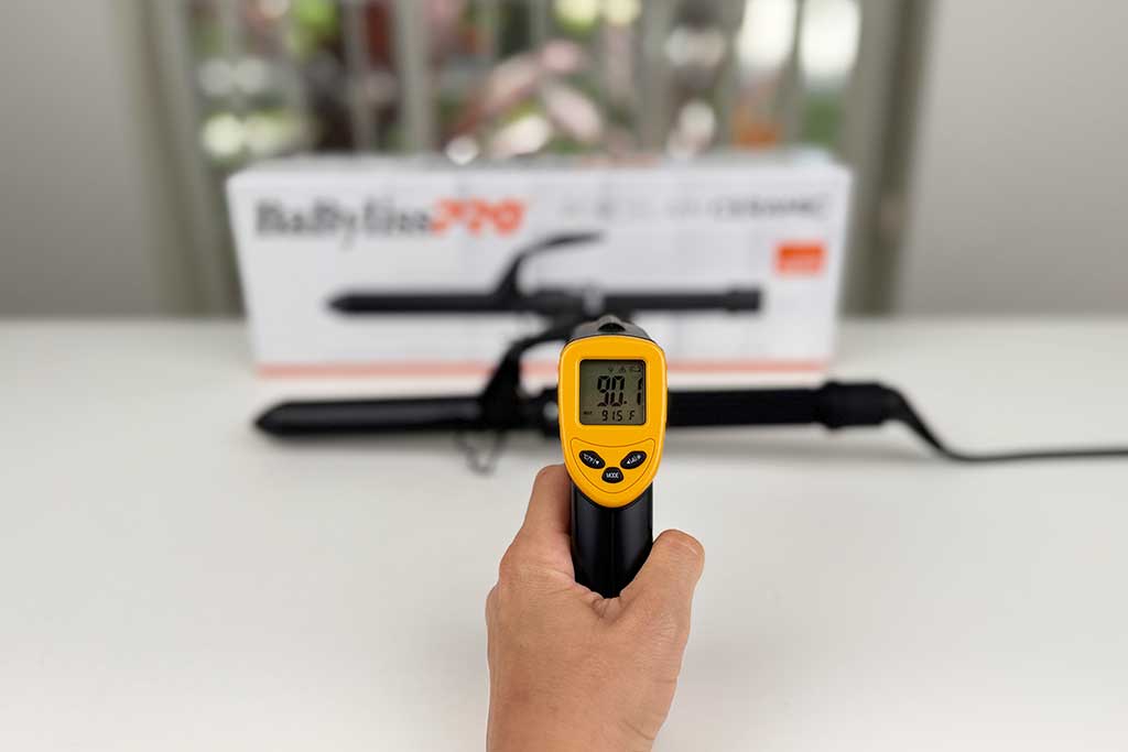 Infrared thermometer measuring 90°F on the cool finger grip of the BaBylissPRO Spring Curling Iron.