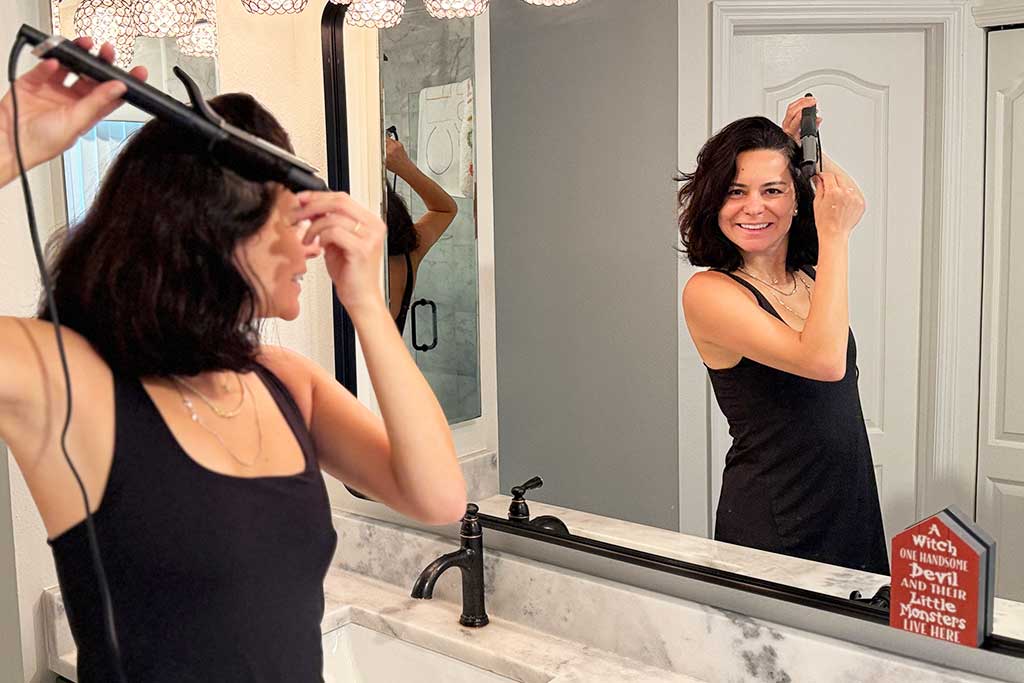 Woman with mid-length hair using the GHD Classic Curl Curling Iron, showing polished, uniform curls.