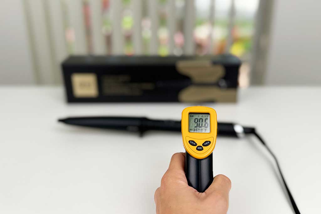 Infrared thermometer showing 90°F aimed at the handle of the GHD Creative Curl Wand.