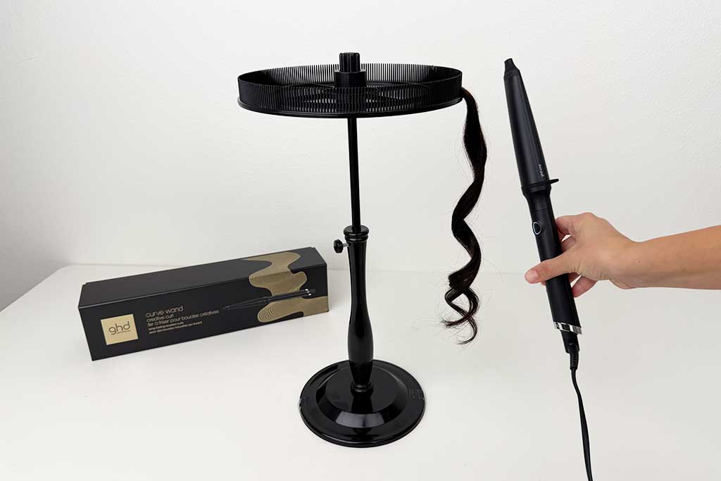 Woman styling mid-length hair with the GHD Creative Curl Wand, wrapping hair around the tapered ceramic barrel during the testing process.