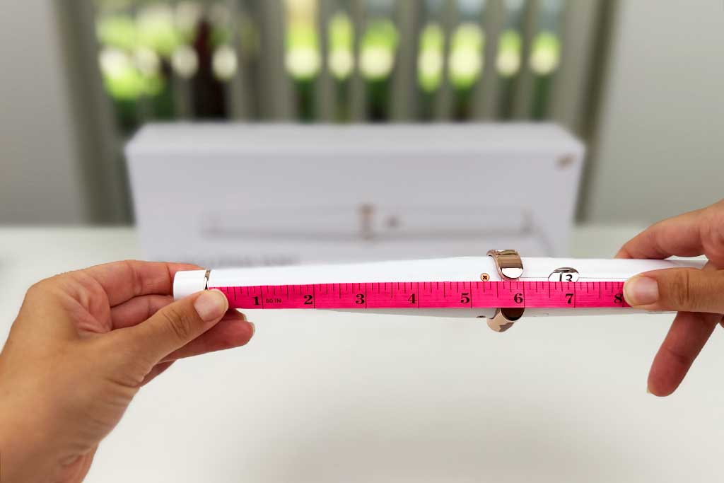 Digital caliper measuring the 5.5-inch ceramic barrel length of the T3 SinglePass Wave curling wand.