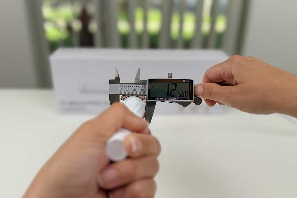 Digital caliper measuring the bottom of the T3 SinglePass Wave curling wand barrel, showing 1.25 inches at the widest point.