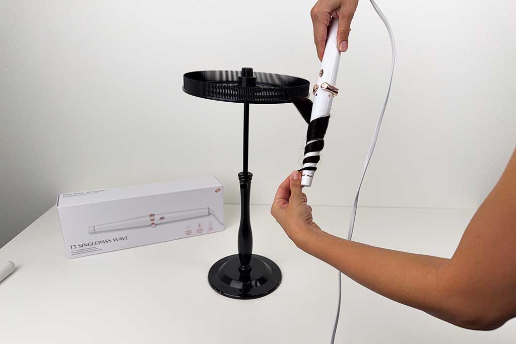 Hand wrapping wig hair around the tapered barrel of the T3 SinglePass Wave curling wand during testing.