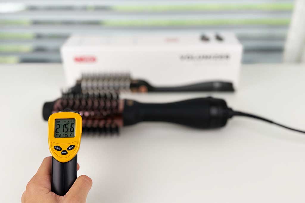 Infrared thermometer showing high heat reading of ~215°F on TYMO VOLUMIZER barrel