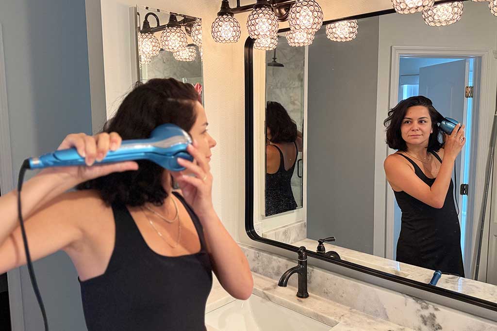 Woman with mid-length, thick hair using BaBylissPRO MiraCurl 3 to create curls.