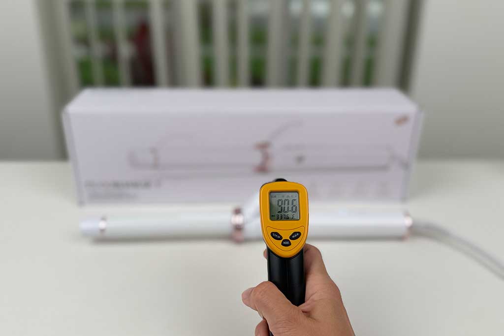 Infrared thermometer displaying 90°F aimed at the finger grip area of the T3 CurlWrap curling iron.