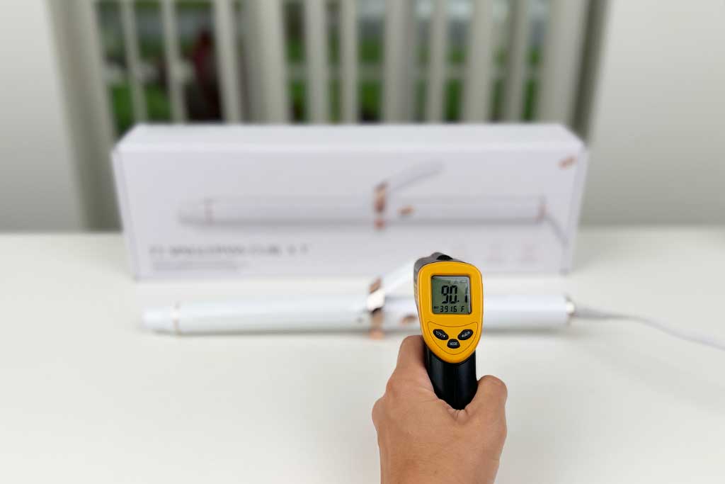 Infrared thermometer displaying 90°F while aimed at the finger grip of the T3 SinglePass Curl X curling iron.