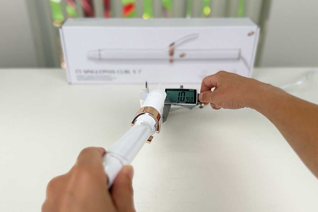 Digital caliper measuring the 1.1-inch handle width of the T3 SinglePass Curl X curling iron.