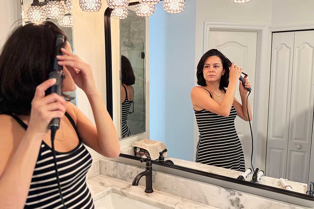 Person curling medium-length hair with the T3 SinglePass Curl curling iron, showing shiny, uniform curls.