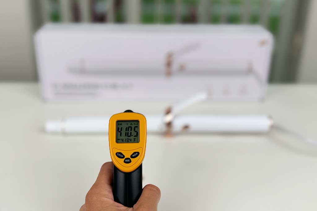 Infrared thermometer displaying 410°F while pointed at the ceramic barrel of the T3 SinglePass Curl X curling iron.